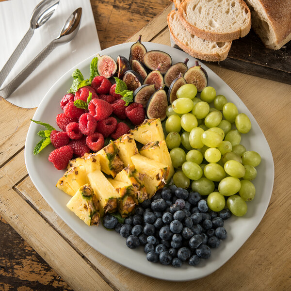 A Carlisle cement melamine oblong platter with fruit and bread on a table.