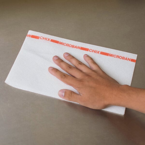 A person's hand on a white and red Chicopee foodservice towel.