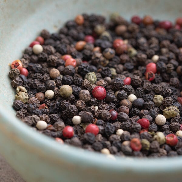 A bowl filled with black, red, and white peppercorns.