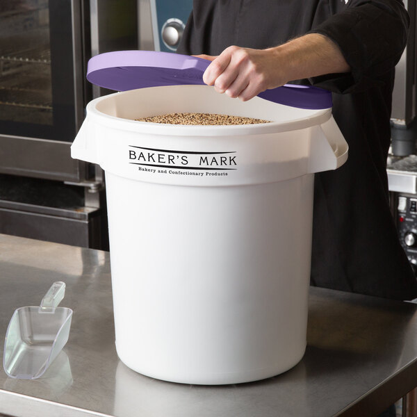 A woman holding a white Baker's Mark ingredient storage bin with a purple lid.