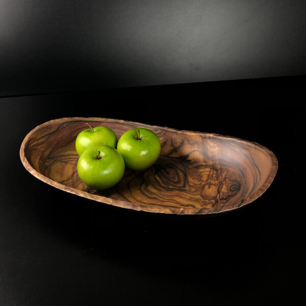An oval wood grain melamine bowl with a group of green apples on a wooden surface.