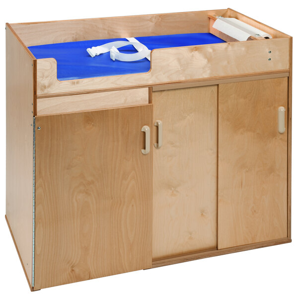 A Whitney Brothers wooden changing table with a blue sheet.