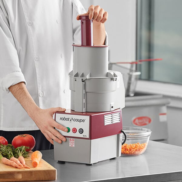 A chef using a Robot Coupe R2 DICE food processor to dice tomatoes.