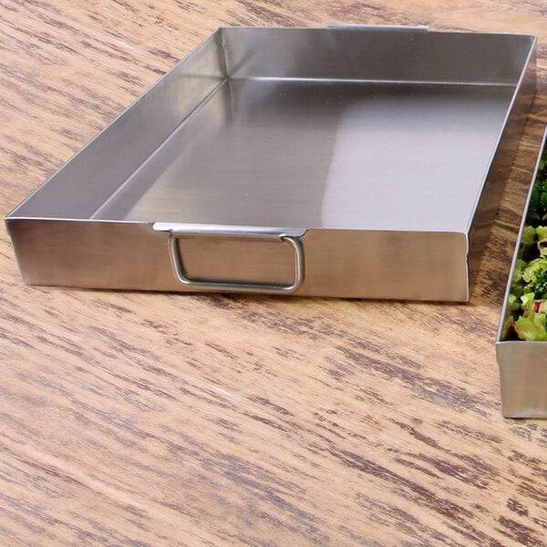 An Elite Global Solutions stainless steel rectangular food pan tray with handles holding a container of green vegetables.