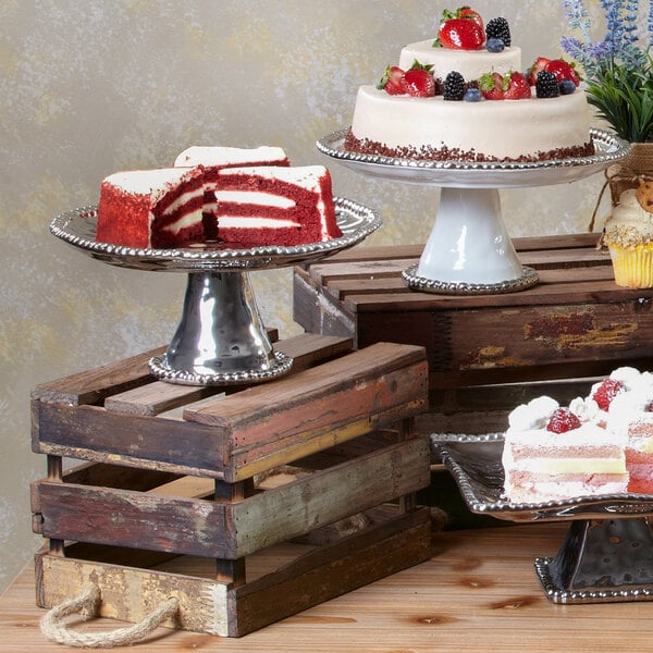 A group of red velvet cakes and cupcakes displayed on a table using a wooden rectangular crate set.