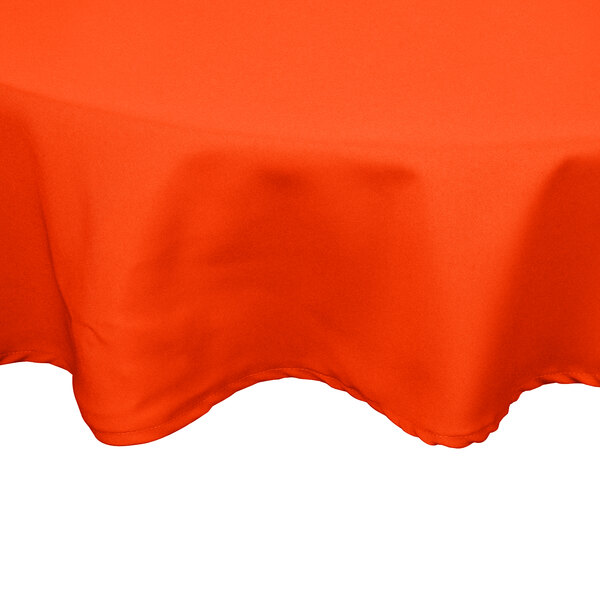 An Intedge orange poly/cotton blend round table cover on a table.