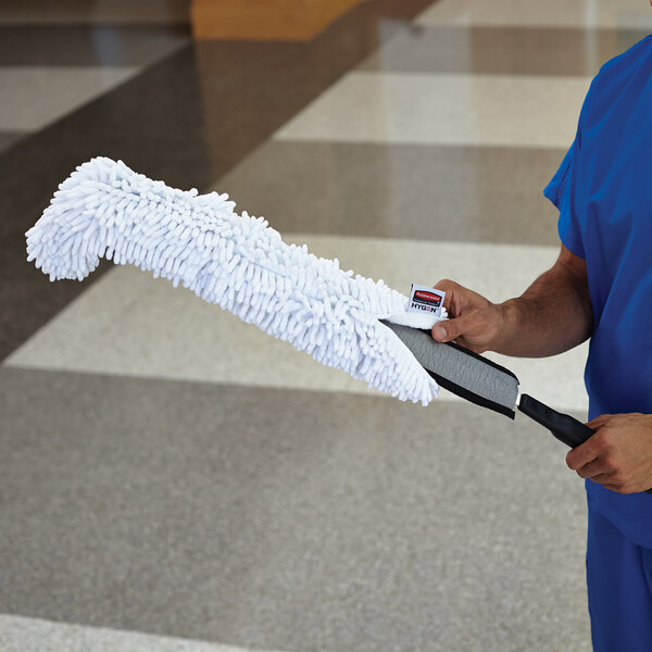 A man in scrubs holding a Rubbermaid White Microfiber Dusting Sleeve.