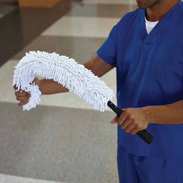 A man in blue scrubs using a Rubbermaid white flexi-wand duster.