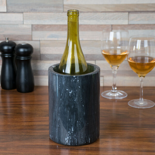 A black marble Tablecraft wine cooler holding a green wine bottle on a wood table.