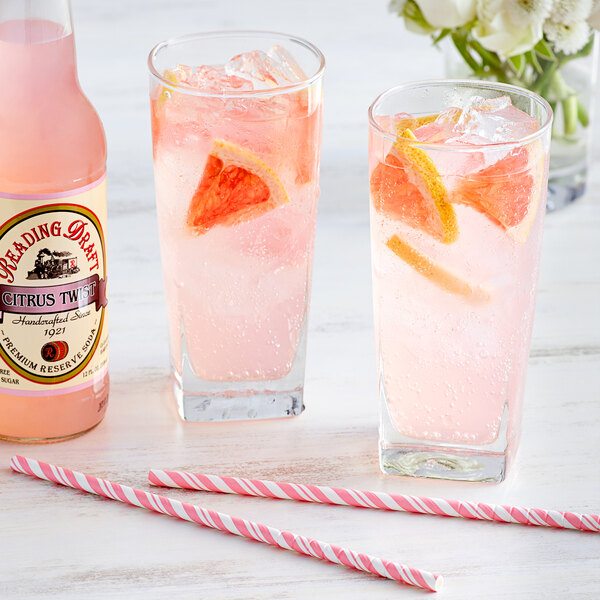 Two glasses of pink Reading Soda Works Citrus Twist with ice and orange slices.