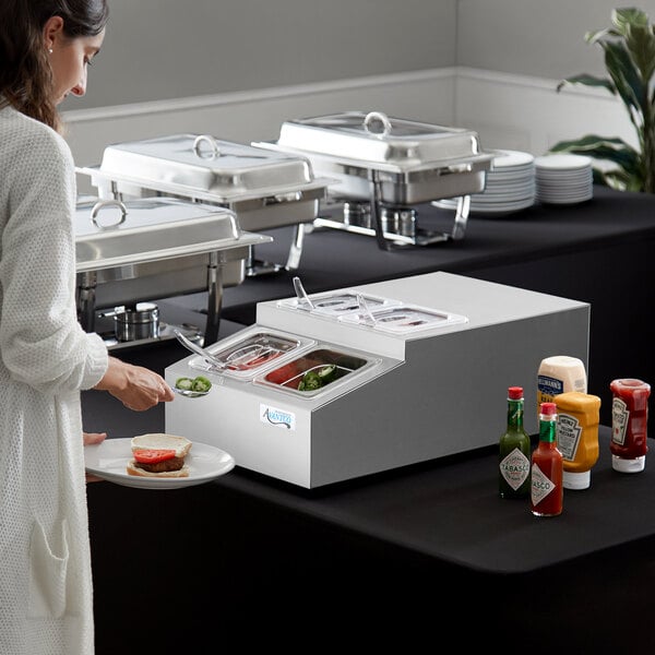 A woman in a white coat uses the Avantco Countertop Refrigerated Prep Rail to serve food at a buffet.