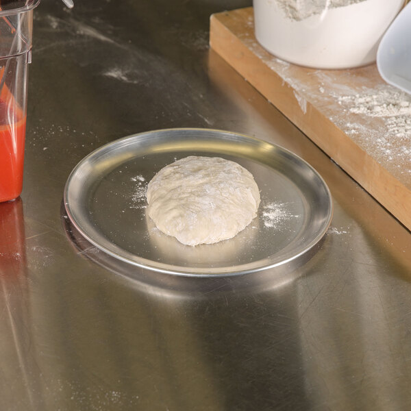 A dough being prepared on an American Metalcraft aluminum pizza pan.