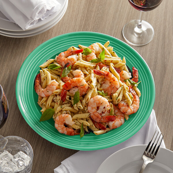 A Tuxton Concentrix cilantro china plate with shrimp pasta and basil on a table.