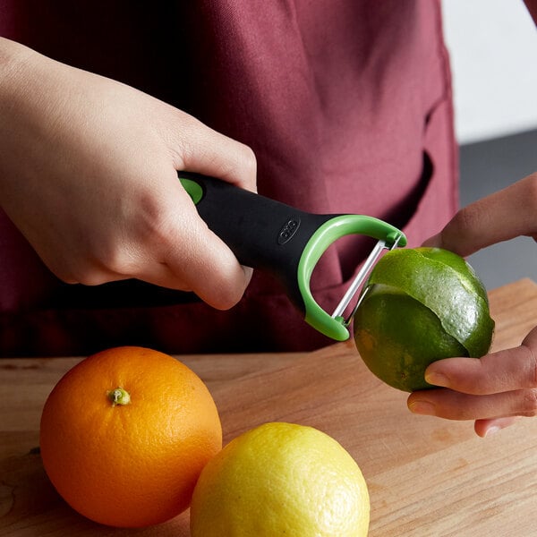 A hand using an OXO citrus peeler to prep a lemon.