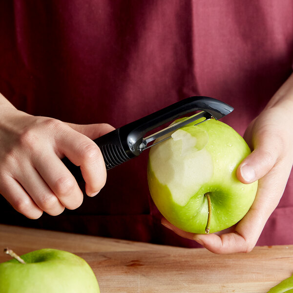 A person using an OXO Good Grips straight vegetable peeler to peel an apple.