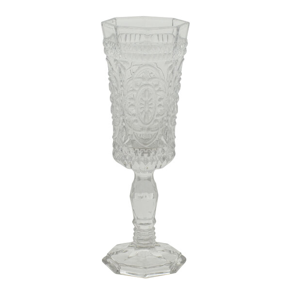 A clear glass wine flute with an ornate design.