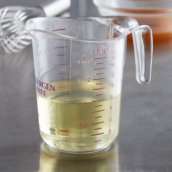 A close-up of a purple plastic measuring cup with yellow liquid in it.