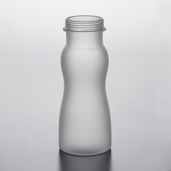 A frosted polycarbonate salad dressing bottle with a lid on a table.