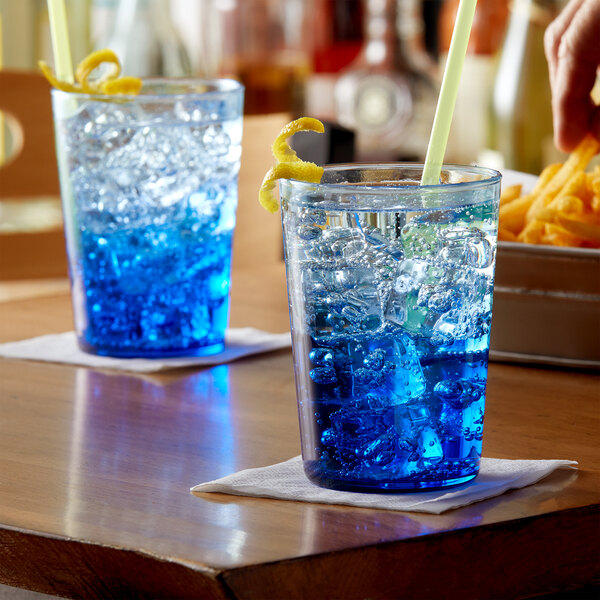 Two Arcoroc blue beverage glasses filled with blue liquid and ice cubes.