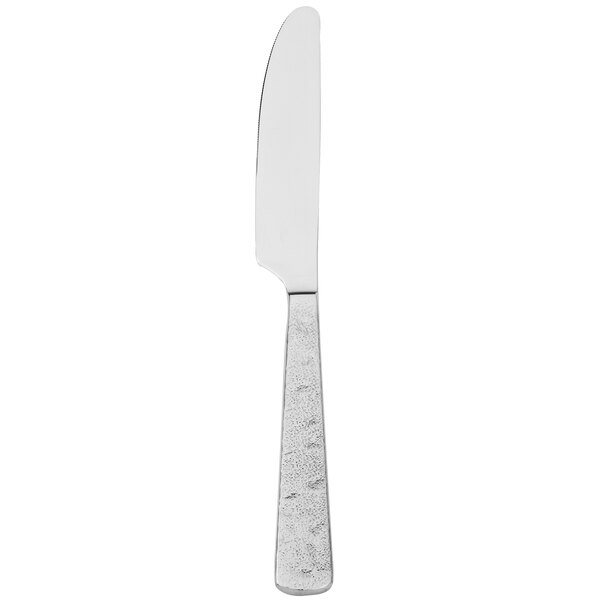 A silver Walco Vestige dinner knife with a white handle.
