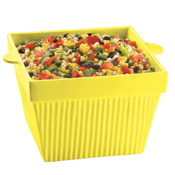 A yellow Tablecraft square condiment bowl with a variety of vegetables in it.