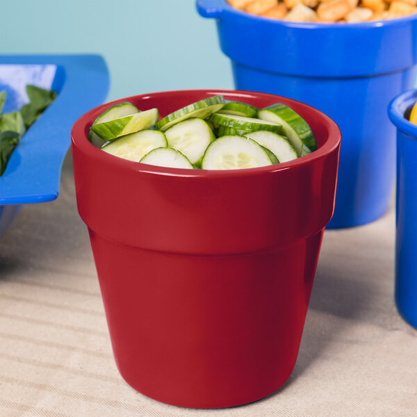 A Tablecraft red cast aluminum round condiment bowl filled with cucumbers.