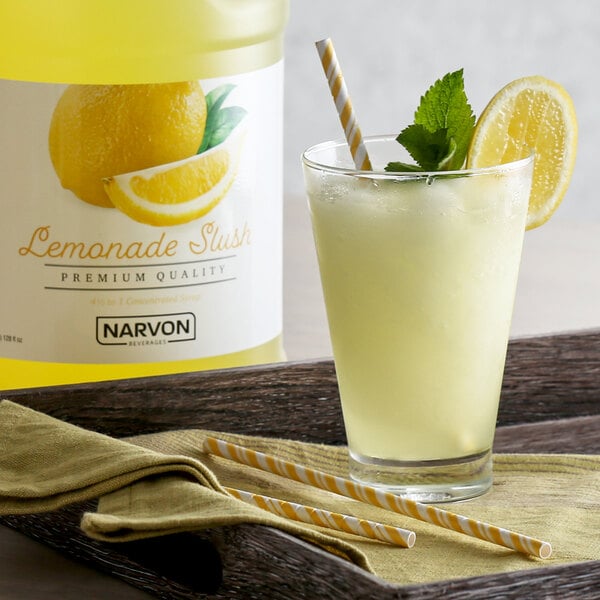 A glass of Narvon lemonade with a yellow and white striped straw and a lemon wedge.