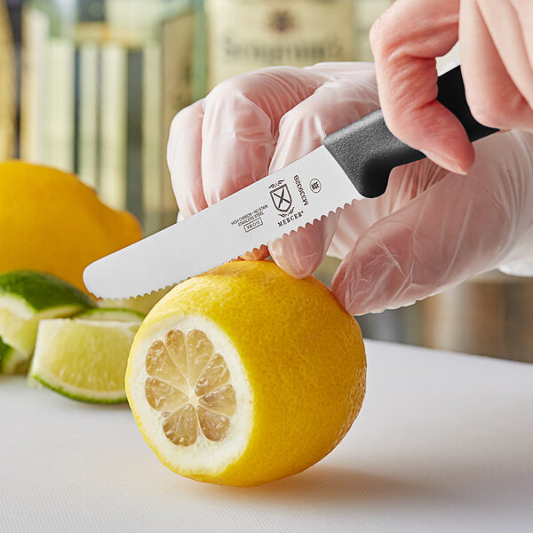 A person using a Mercer Culinary paring knife to cut a lemon.