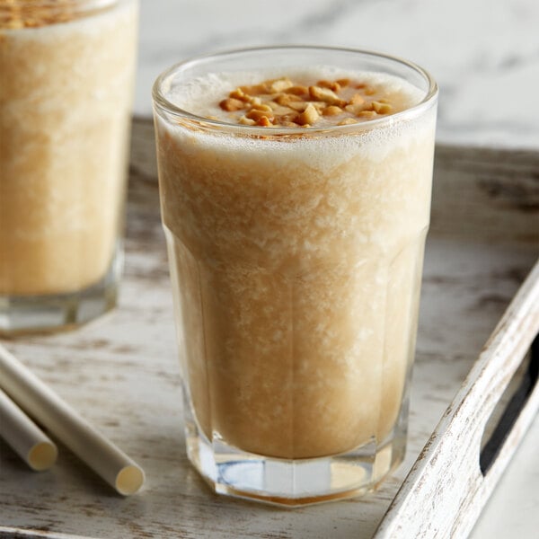 A glass of milkshake with DaVinci Gourmet Peanut Butter syrup and nuts.