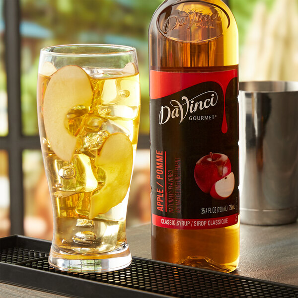 A glass of apple juice with DaVinci Gourmet Classic Apple Flavoring on the table.