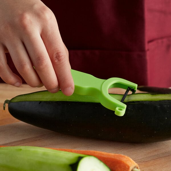 A hand using a green Mercer Culinary "Y" vegetable peeler to peel a cucumber.