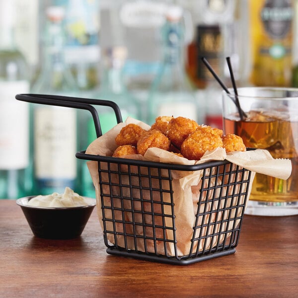 A black Acopa square mini fry basket filled with fried food and a drink.