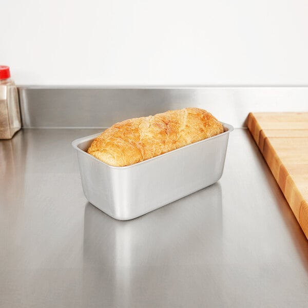 A loaf of bread in a Vollrath anodized aluminum loaf pan on a counter.