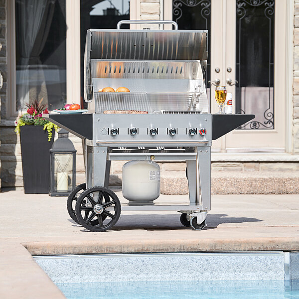 A Crown Verity natural gas outdoor grill on a cart with a roll dome cover.