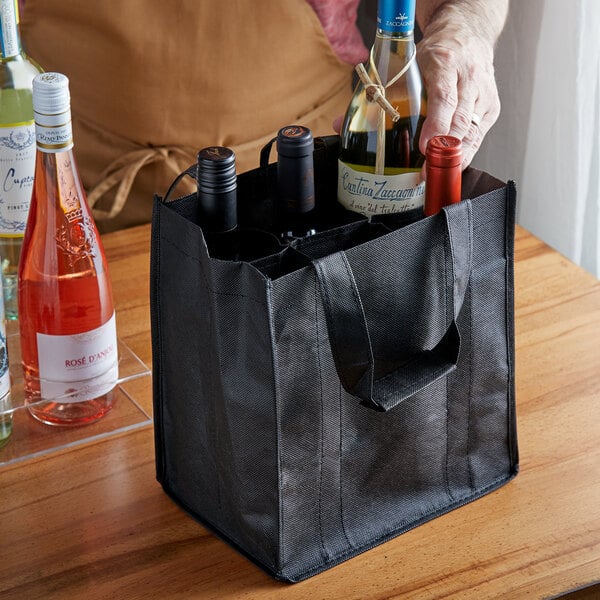 A person putting bottles of wine in a black Franmara reusable bag.