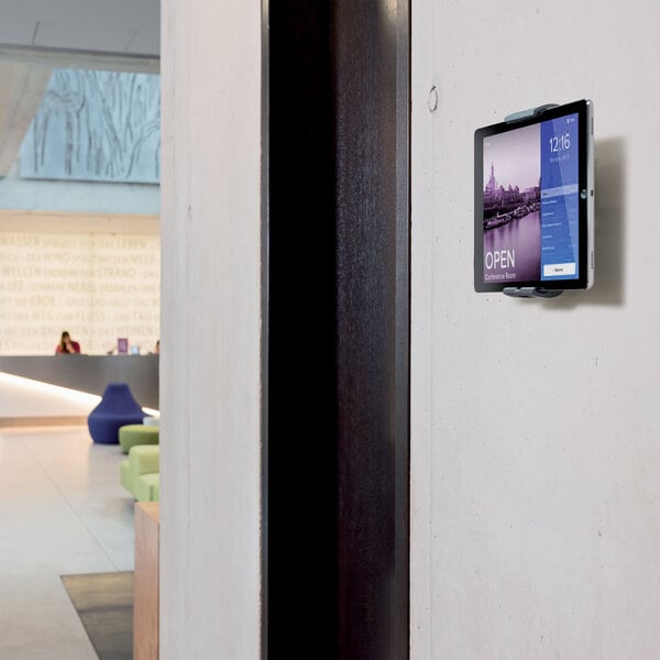 A Durable silver metal tablet holder mounted on a wall with a tablet in it.