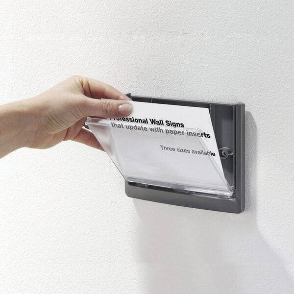 A hand putting a paper in a Durable silver sign holder with clear acrylic click window.