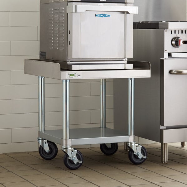 A Regency stainless steel equipment stand with casters and an undershelf holding a large stainless steel oven.
