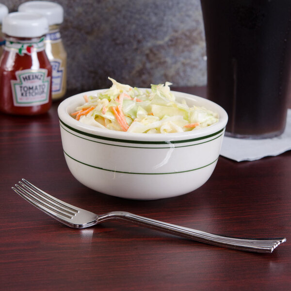 A Tuxton Jung soup bowl filled with coleslaw with green bands on a table.
