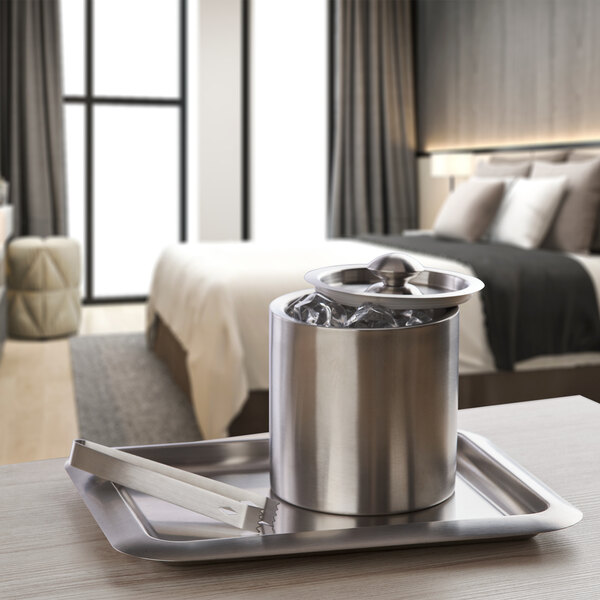 A Focus Hospitality stainless steel rectangular beverage tray with ice in a silver container and tongs.