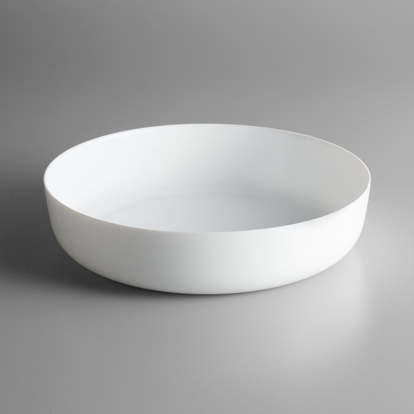 An Arcoroc white opal glass serving bowl on a gray surface.