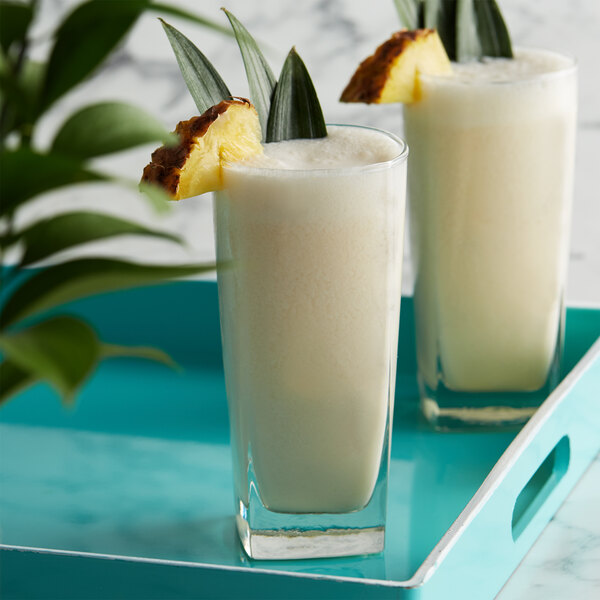 Two glasses of white liquid with pineapple slices on top using DaVinci Gourmet Sugar Free Coconut Flavoring Syrup.