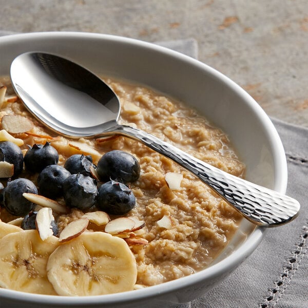 A bowl of oatmeal with blueberries, bananas, and a spoon.