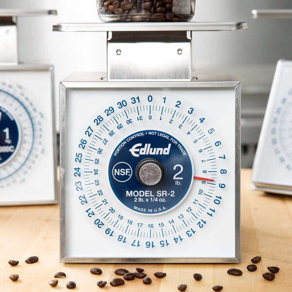 An Edlund mechanical portion scale with a dial and coffee beans on top.