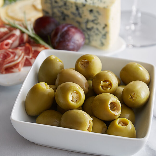 A bowl of green olives with cheese on a table.