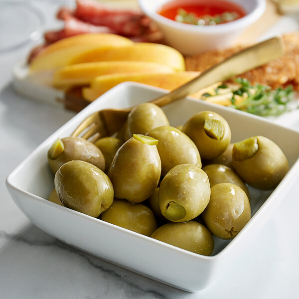 A bowl of Belosa dill pickle stuffed green olives on a table in a deli.