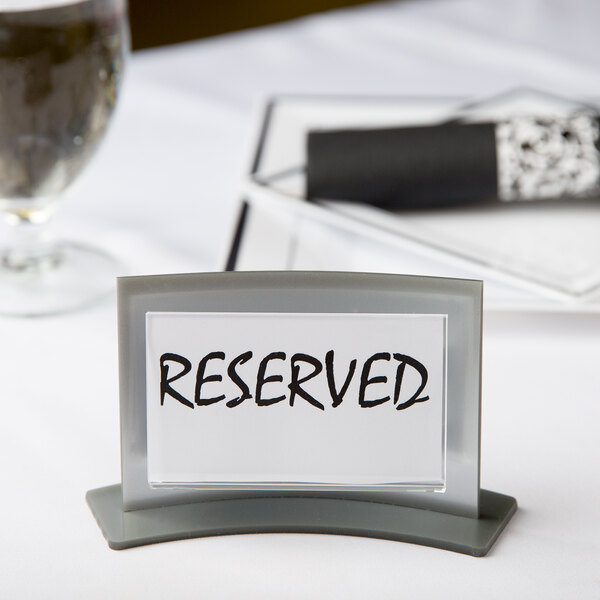 A reserved sign in a Cal-Mil Forma displayette on a table with a wine glass.