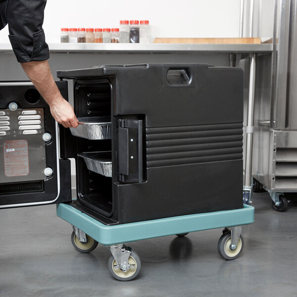 A man using a Slate Blue Cambro Camdolly to open a black food container.