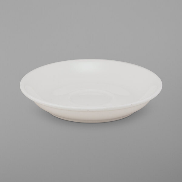 A bright white porcelain saucer with a small rim on a white surface.