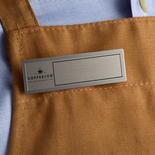 A brown apron with a Cawley silver metal rectangle name tag.